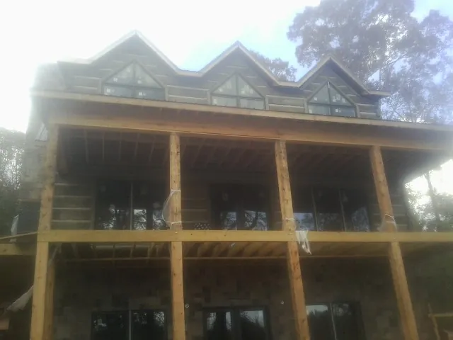 Dormers and porch framing on a large log home under construction — Roof Coating work by our crew in Chadwicks