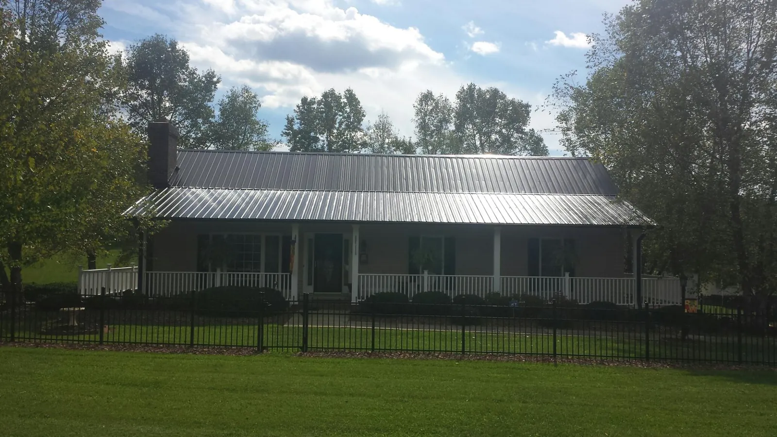 Gray metal roof on a brick ranch with a full width front porch — Gutter Guard Installation work by our crew in Chadwicks