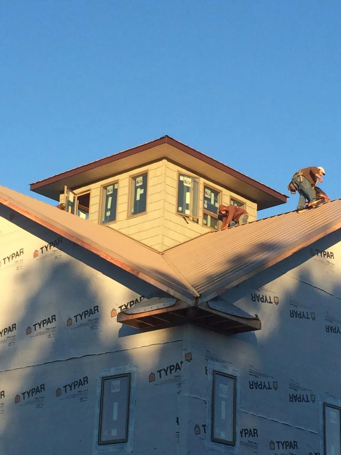 Roofers working around a rooftop cupola on a new metal roof at sunset — Roof Waterproofing in Chadwicks by Roofing Brothers